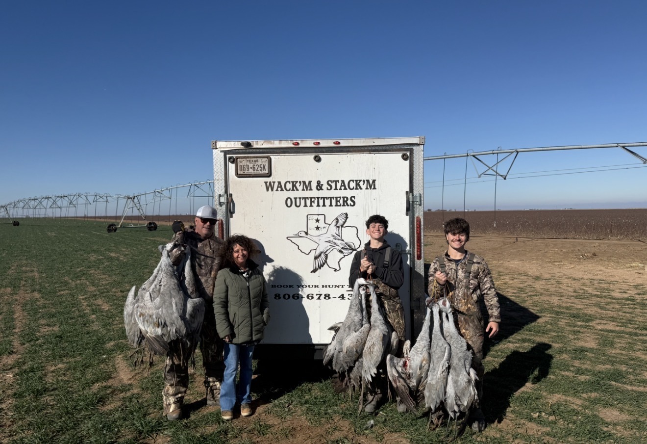 Wack'm & Stack'm crew with a successful sandhill crane hunt next to their branded trailer